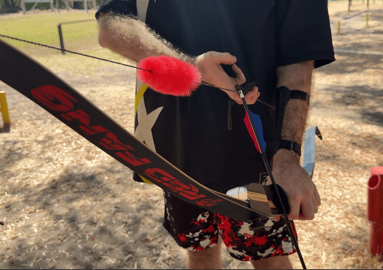 Red fur string silencer attached to a bowstring, demonstrating its effectiveness in dampening sound and vibration.