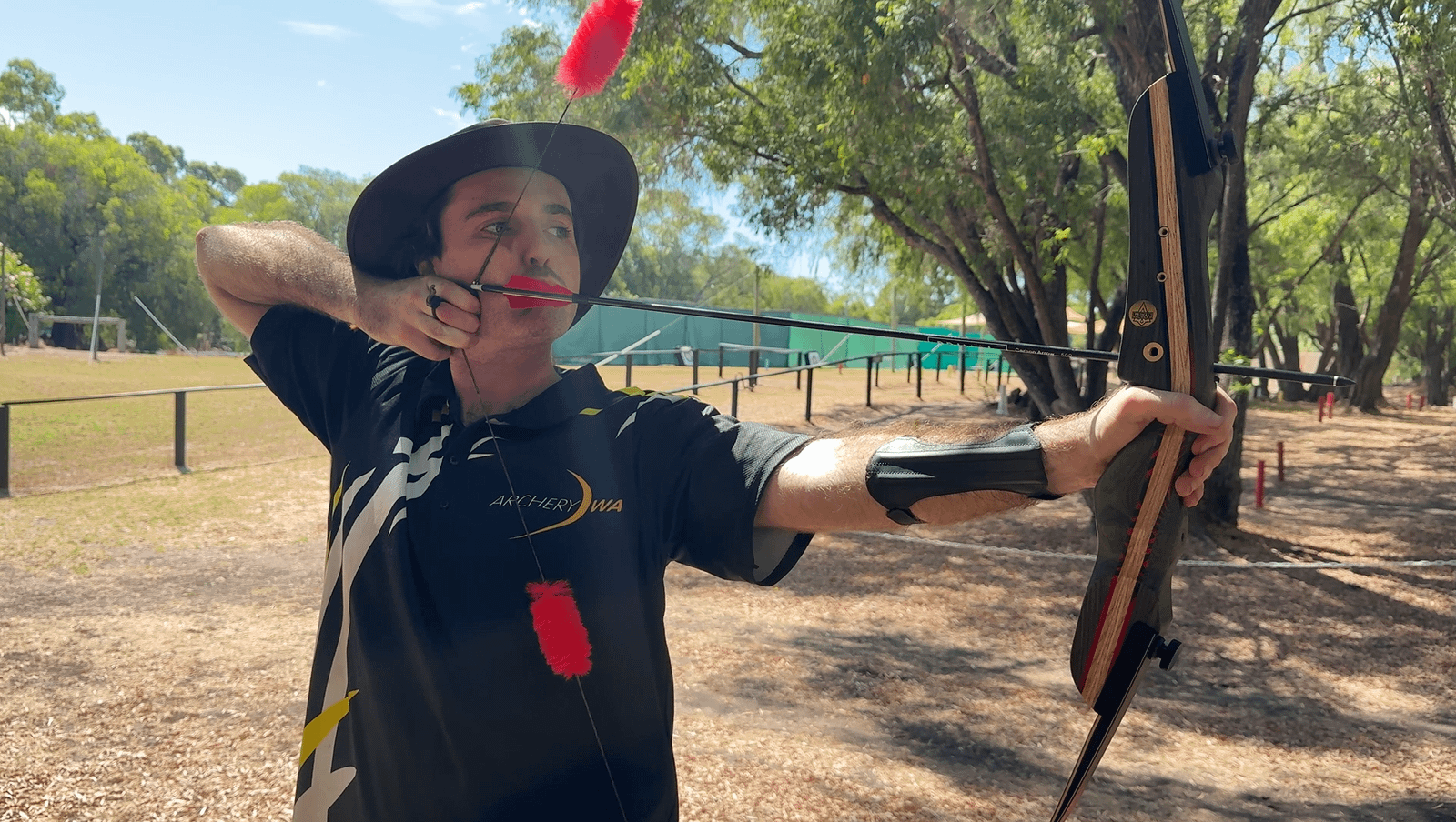 Archer drawing a recurve bow equipped with fur string silencers, enhancing stealth and reducing string vibration.