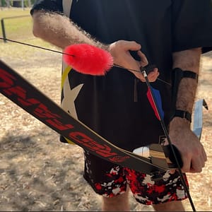 Red fur string silencer attached to a bowstring, demonstrating its effectiveness in dampening sound and vibration.