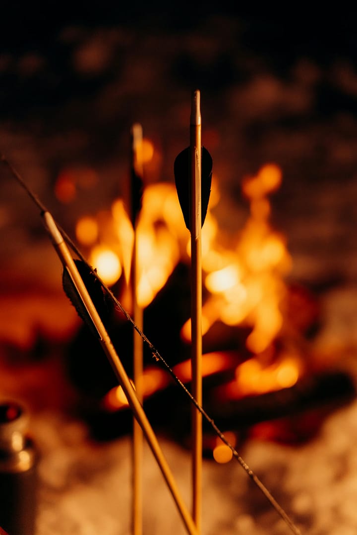 Wooden arrows standing beside a campfire at night
