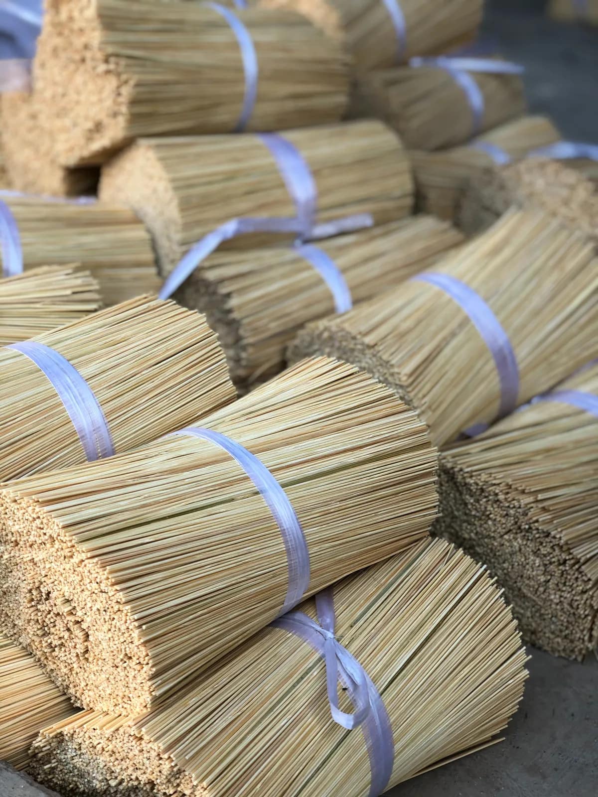 Bundles of undyed incense sticks tied with bands and stacked, waiting to be finished.